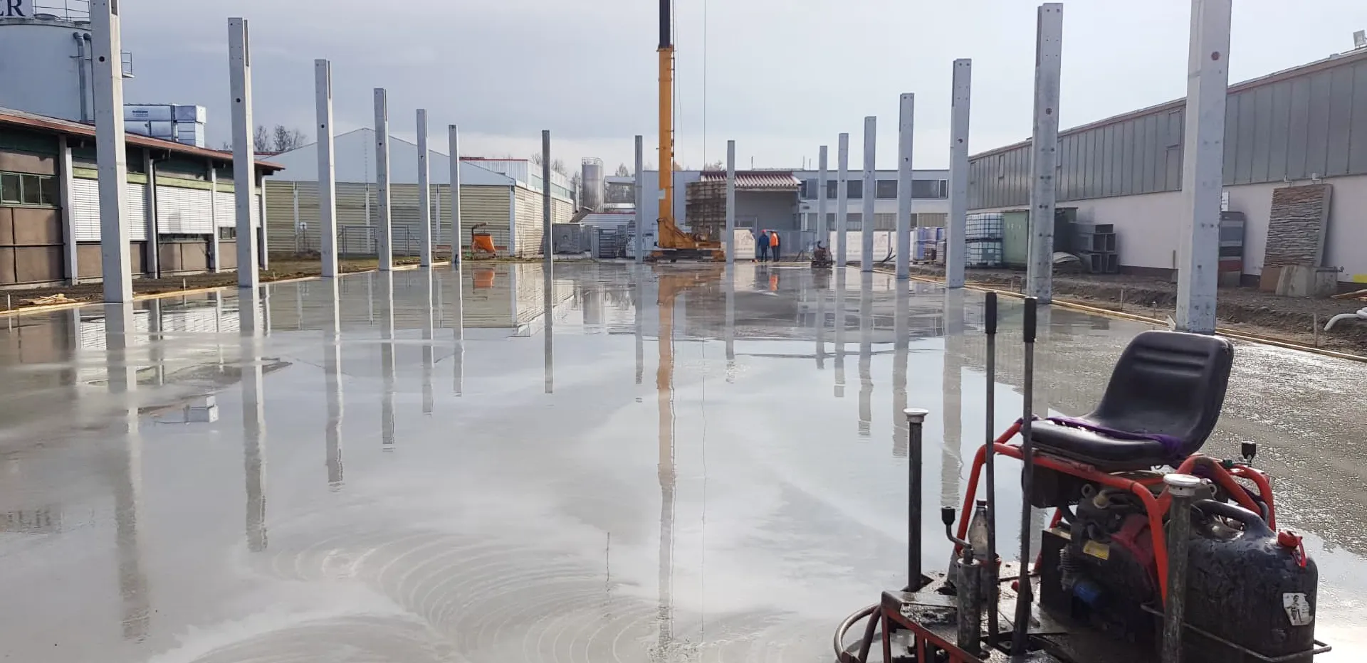 Nassbetonboden auf Baustelle mit Stahlträgern – Betonbau im Allgäu