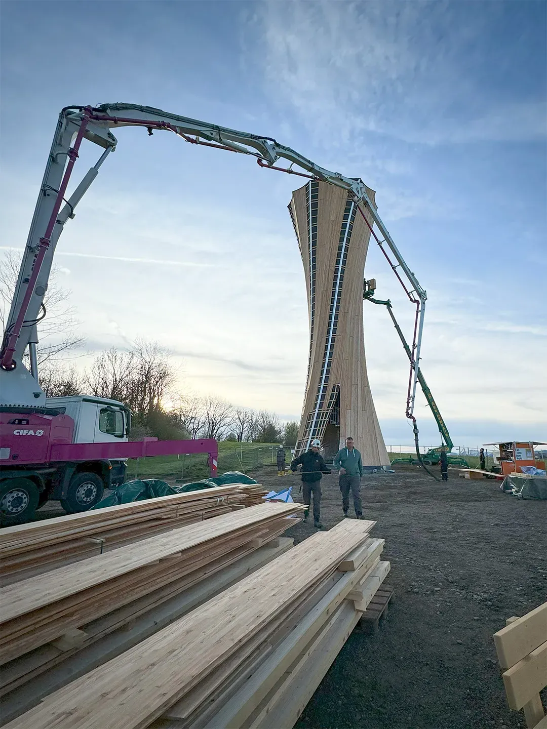 Baustelle mit modernem Holzbau, Betonpumpen im Einsatz und aufgehenden Bauwerken
