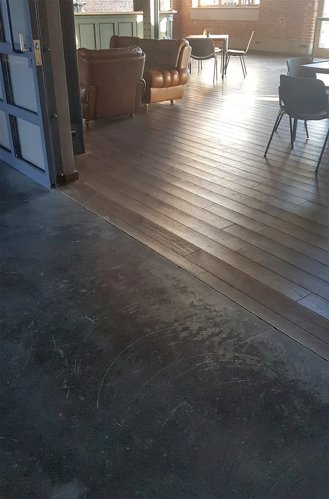 Übergang zwischen dunklem Betonboden und hellbraunem Holzboden in einem stilvoll eingerichteten Raum