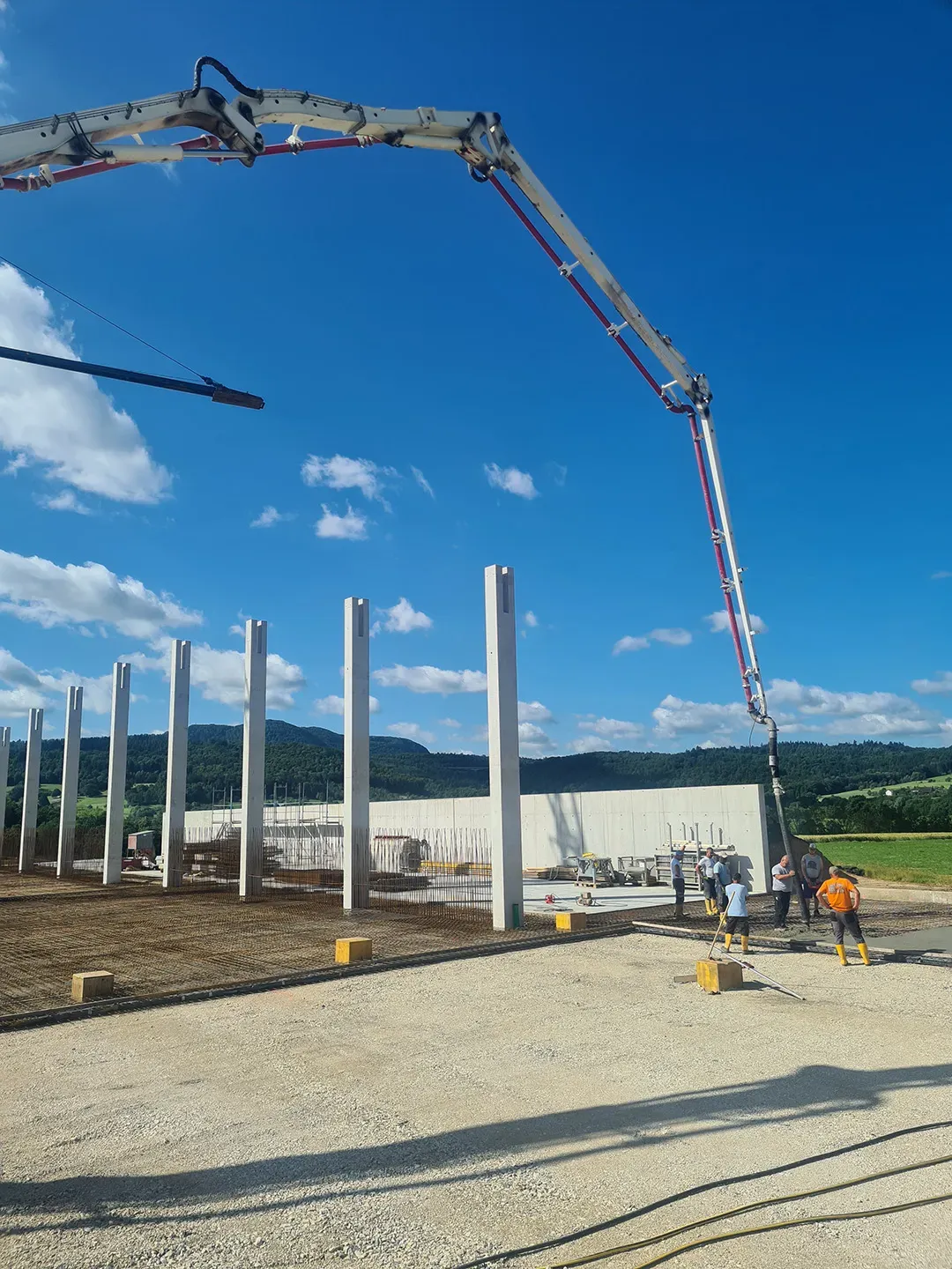 Betonierarbeiten auf einer Baustelle mit Vertikalstützen und blauem Himmel im Hintergrund