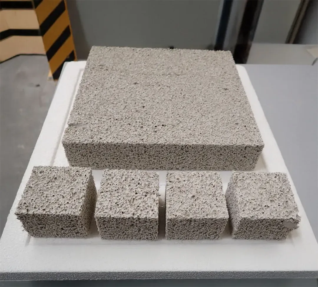 Verschiedene Blöcke porösen, grauen Dämmmaterials auf einer weißen Unterlage