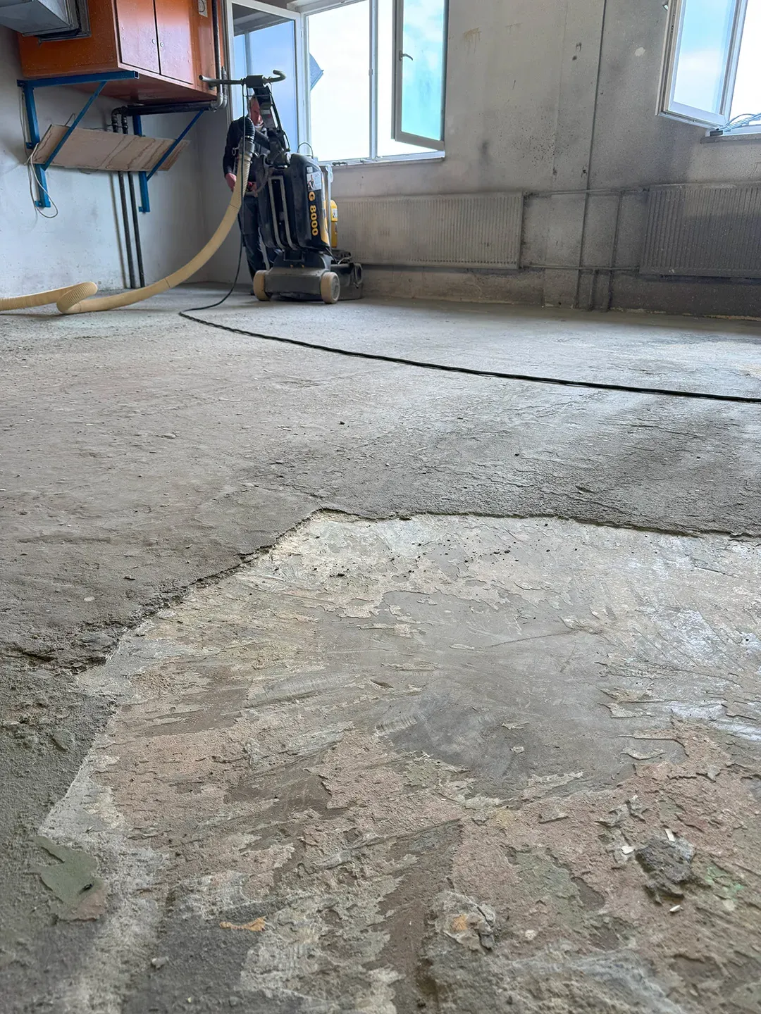 Abgenutzter Betonboden während einer Sanierungsmaßnahme mit Schleifmaschine
