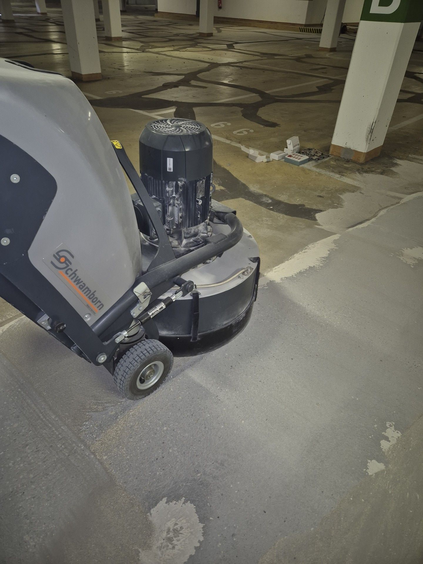 Bauhalle mit Betonboden während der Bearbeitung und Schleifmaschinen im Einsatz