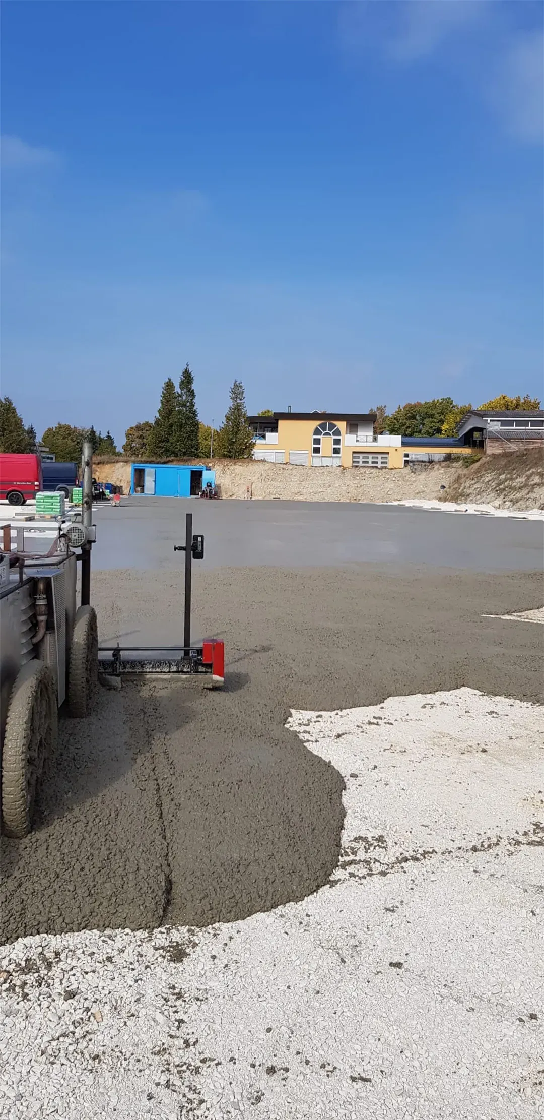 frisch gegossene Betonfläche auf einer Baustelle mit sichtbarer Ausrüstung
