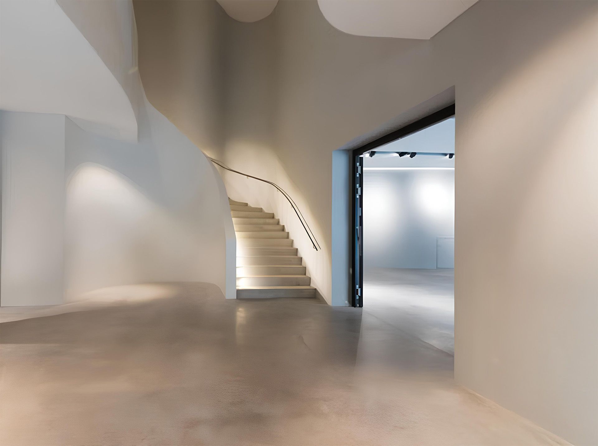 Heller, minimalistischer Innenraum mit geschwungenen Treppen und weichen Übergängen zwischen Wänden und Decken.